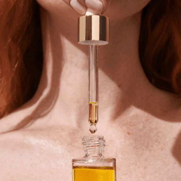 Woman applying Lumity Facial Oil to neck for firm, hydrated skin