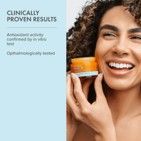 Smiling woman holding The Organic Pharmacy Carrot Butter Cleanser 50ml, showcasing its clinically proven gentle cleansing benefits