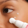 Woman gently applying Dermaceutic Reveal 4x Advanced Eye Serum 15ml to her under-eye area to reduce puffiness.