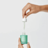 Hand opening a bottle of Biretix Double Correction Serum 30ml, lifting the applicator dropper to show the product packaging and dispensing design.