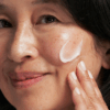 Woman gently applying Neostrata Skin Brightener SPF 35 to her face, demonstrating smooth, lightweight coverage