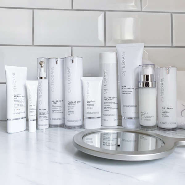Collection of Teoxane skincare products arranged aesthetically on a neutral background, representing advanced dermocosmetic care