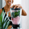 Woman mixing ZENii Fusion Collagen Creamer 2 Pack in a blender with healthy ingredients, supporting skin, hair, nail, and joint health.