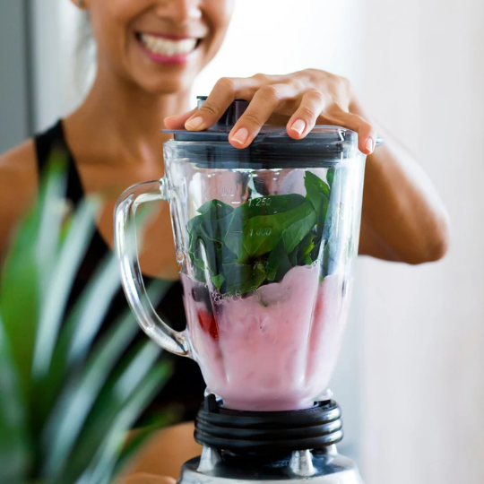 Woman mixing ZENii Fusion Collagen Creamer 2 Pack in a blender with healthy ingredients, supporting skin, hair, nail, and joint health.